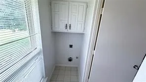 Built-in upper cabinetry, tile flooring, and a large window with blinds