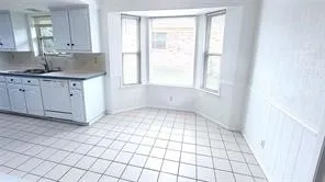 Kitchen area featuring white cabinetry, a built-in dishwasher, a double basin sink, and tile flooring