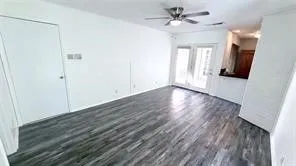Wood-finish flooring throughout, ceiling fan with integrated lighting, and white walls