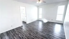 Wood-finish flooring throughout, bright white walls, and a ceiling fan