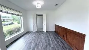 Wood-finish flooring, paneled wainscoting, recessed lighting, and a large window