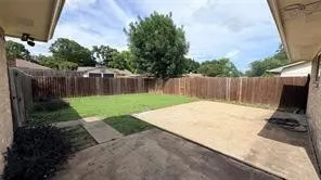 Expansive backyard featuring a wood privacy fence, concrete patio, and a grass lawn