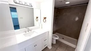 White vanity with integrated sink, chrome faucet, and overhead lighting