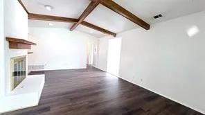 Vaulted ceiling with exposed wood beams, wood-finish flooring, fireplace with hearth, and recessed lighting