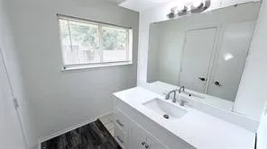 White vanity with integrated sink, chrome faucet, and expansive wall-mounted mirror
