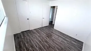 Wood-finish flooring, white walls, and a window with blinds