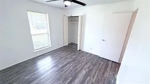 Wood-finish flooring, ceiling fan, and white walls