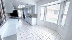 White cabinetry with ample storage, integrated cooktop, double wall ovens, and a skylight