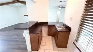 Kitchenette featuring brown wood-finish cabinetry, a single basin sink, and dark countertops