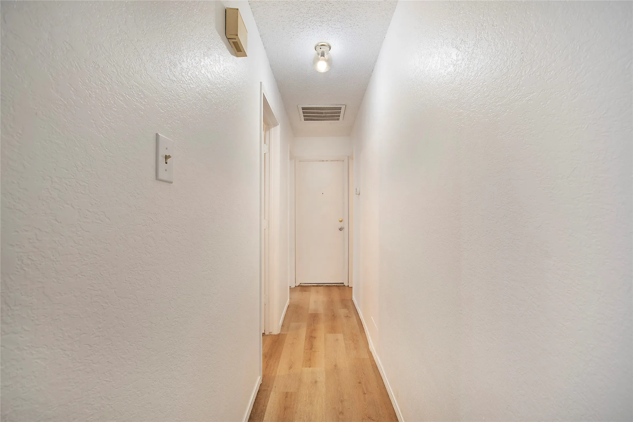 Hallway featuring wood-finish flooring, a flush-mount ceiling light, and neutral wall tones