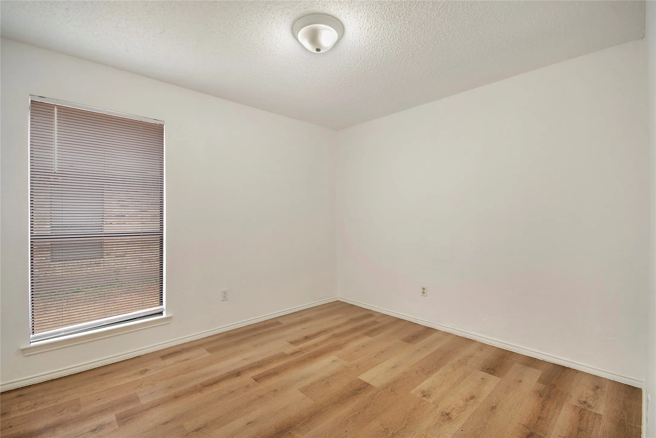 Wood-finish flooring, neutral wall tones, recessed window, and flush mount lighting