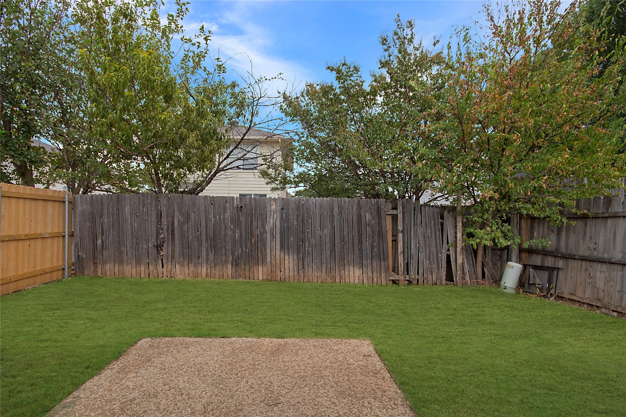 Expansive backyard featuring a concrete patio and manicured lawn