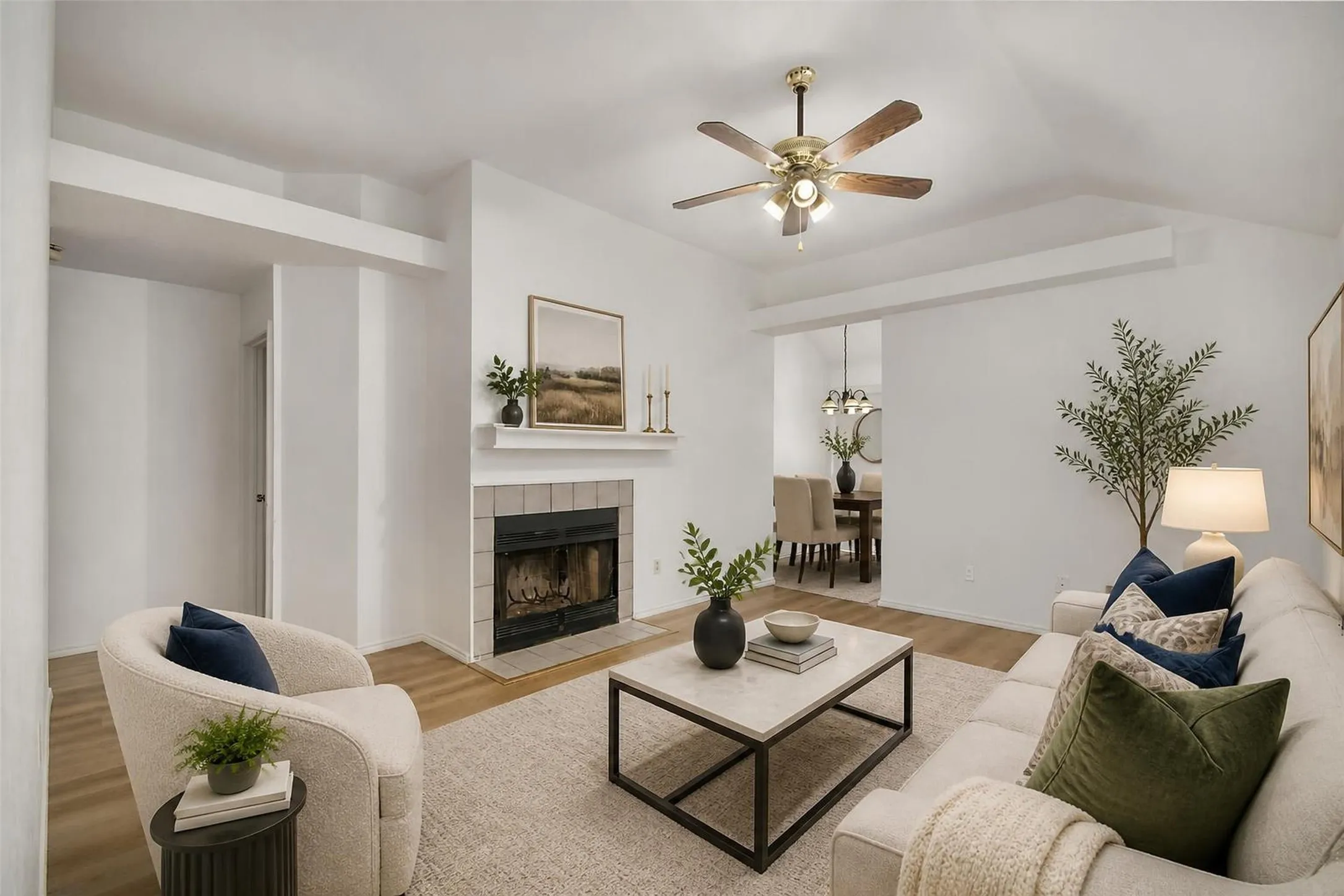 Vaulted ceiling with a ceiling fan, fireplace with a tile surround, and wood-finish flooring