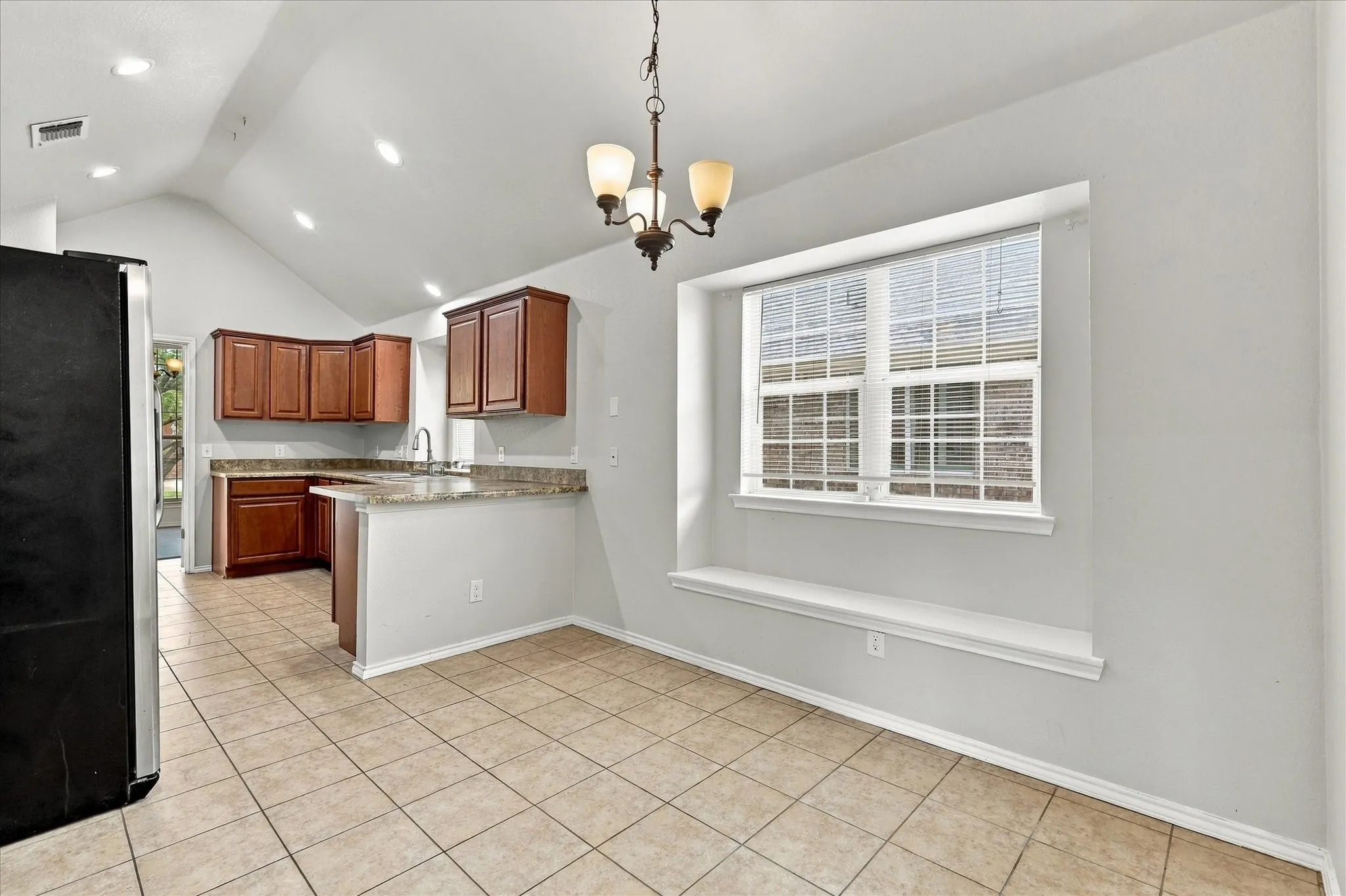 The oversized kitchen offers abundant counter and cabinet space, breakfast bar, electric range, built-in microwave and a sink positioned beneath a window overlooking the side yard. The adjoining breakfast nook features vaulted ceilings, recessed lighting and a built-in window seat.