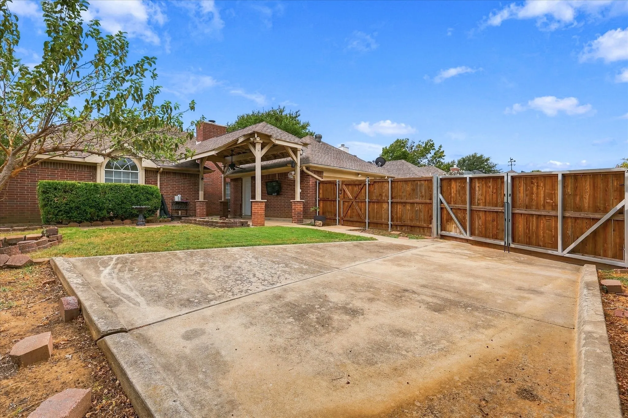 Fenced backyard featuring a concrete parking pad with double gate to park boat or car.