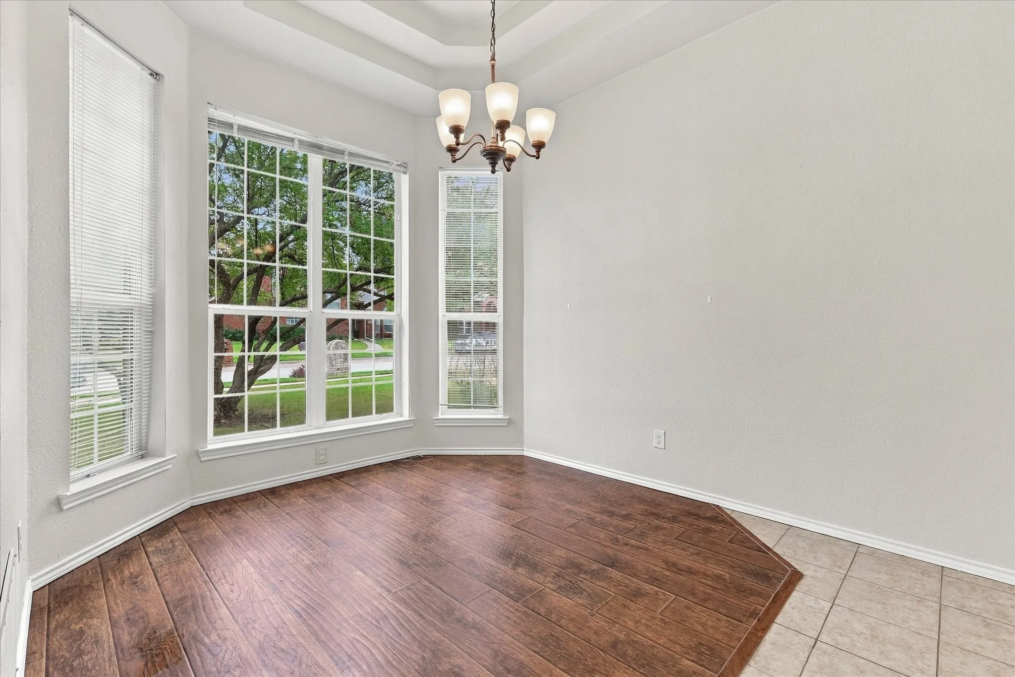 The formal dining room adds an elegant touch with its three-tier tray ceiling, bay window and decorative lighting.