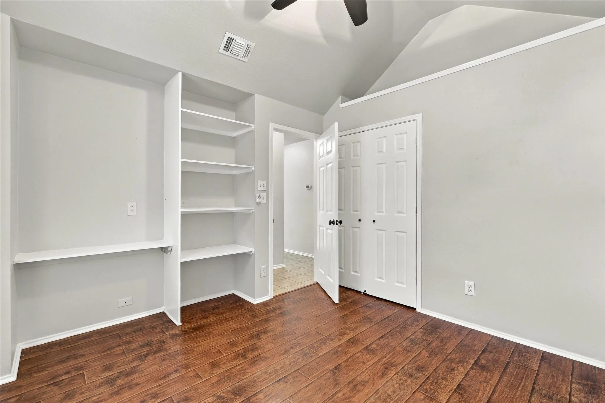 Front Bedroom with vaulted ceiling, ceiling fan and built-in shelving.