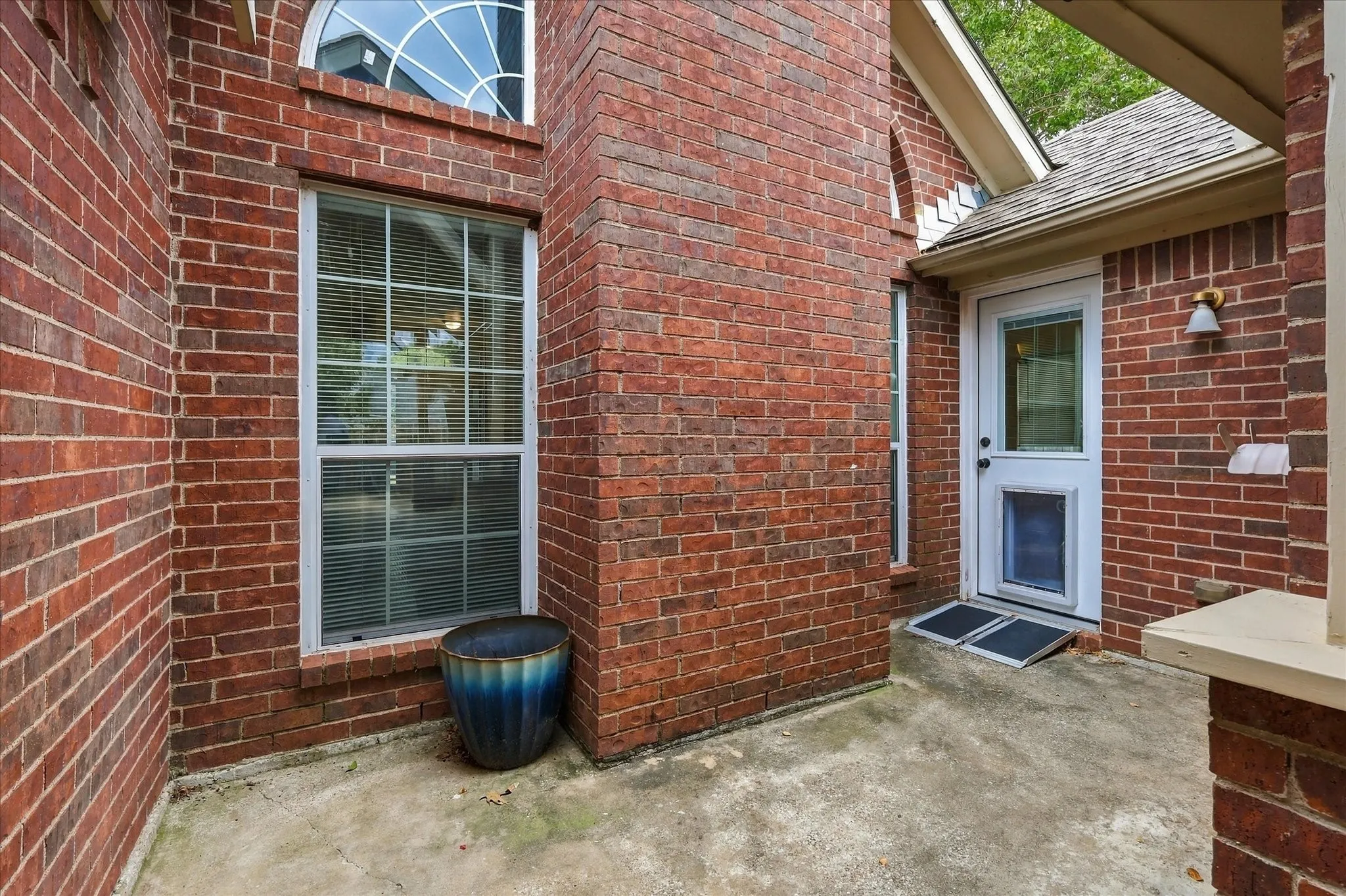 Brick exterior wall with a tall, arched window featuring white grilles