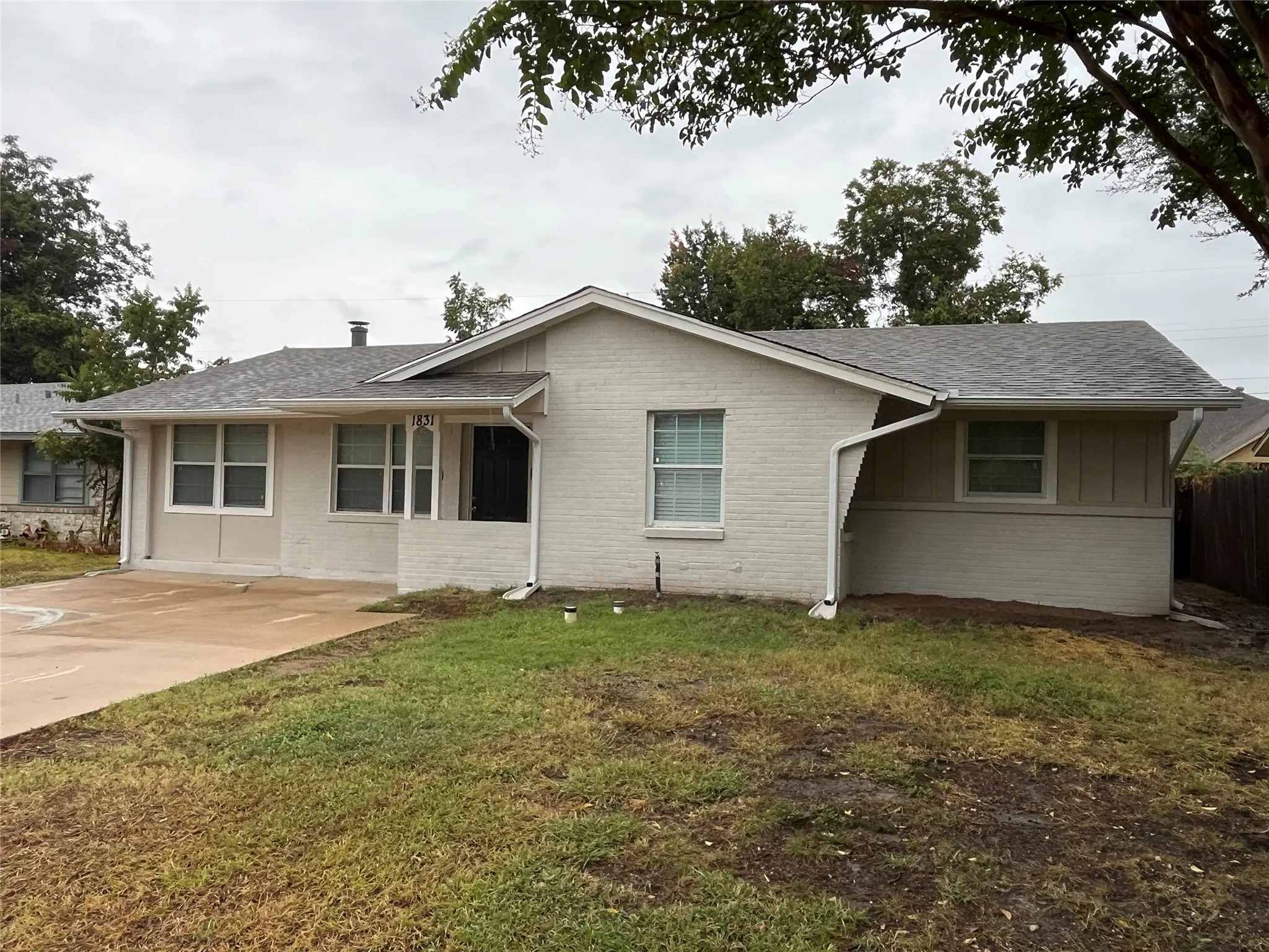 Brick and siding exterior with a shingle roof, complemented by white window frames and a concrete driveway
