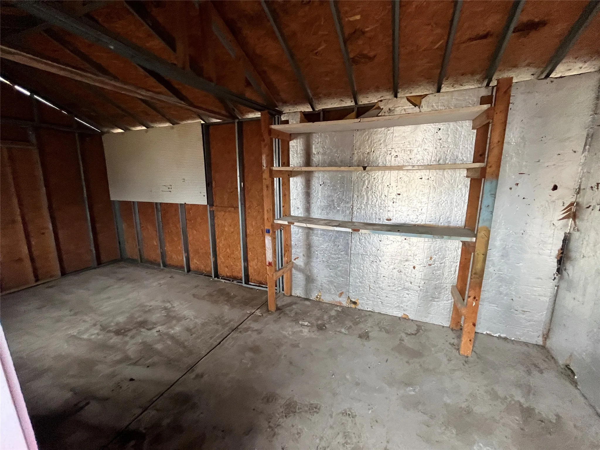 Concrete flooring with exposed ceiling joists and wall studs