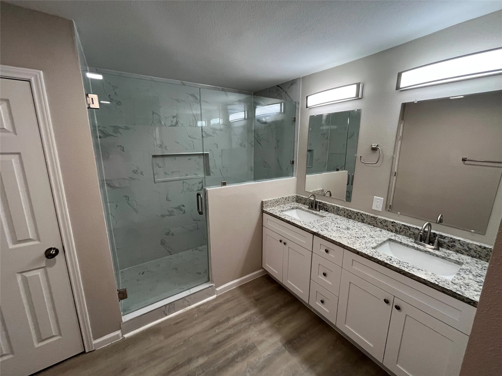 Expansive dual vanity with stone countertops, under-mount sinks, and individual mirrors
