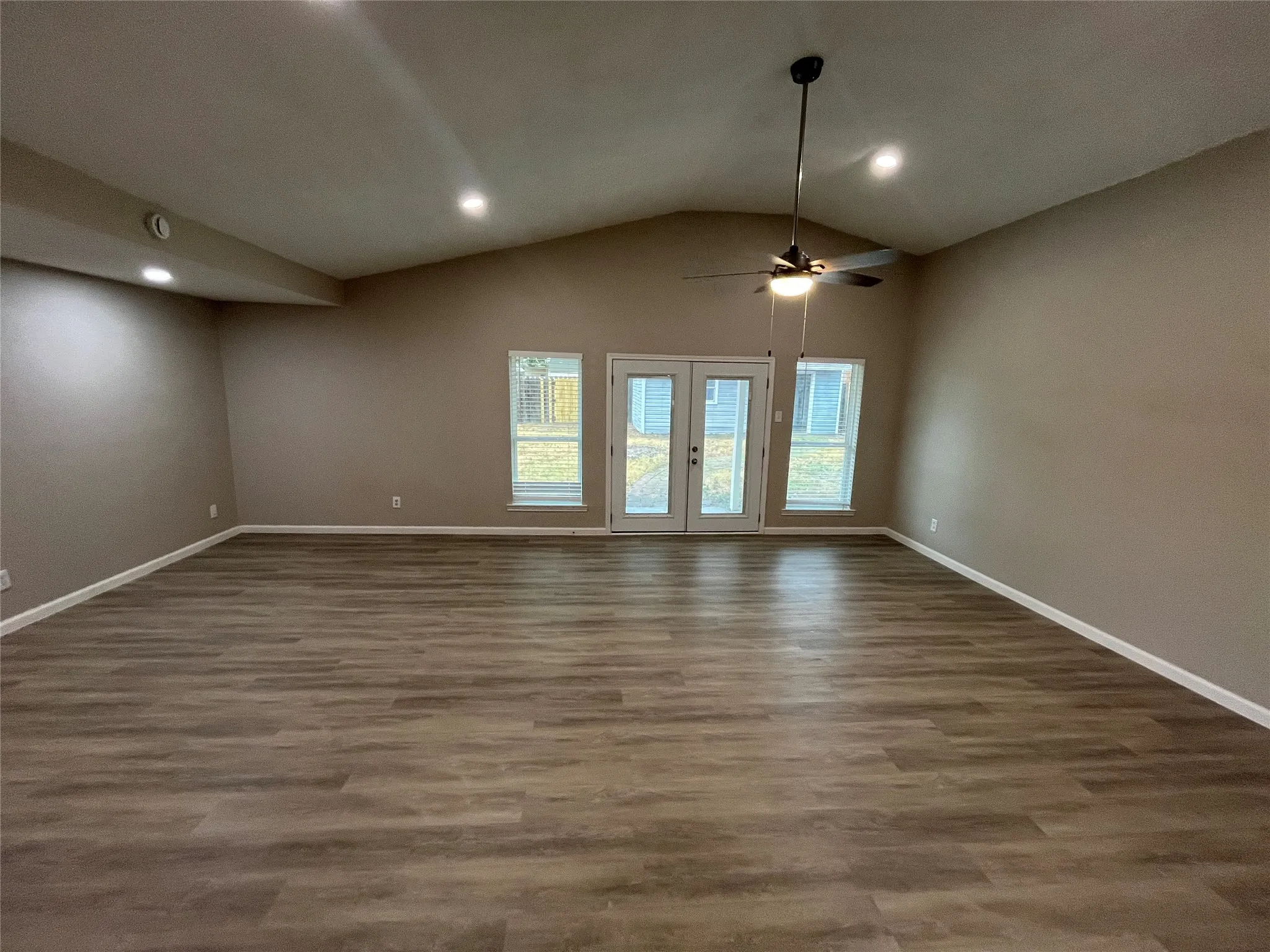 Vaulted ceiling with a ceiling fan, recessed lighting, wood-finish flooring, and double glass-paneled doors