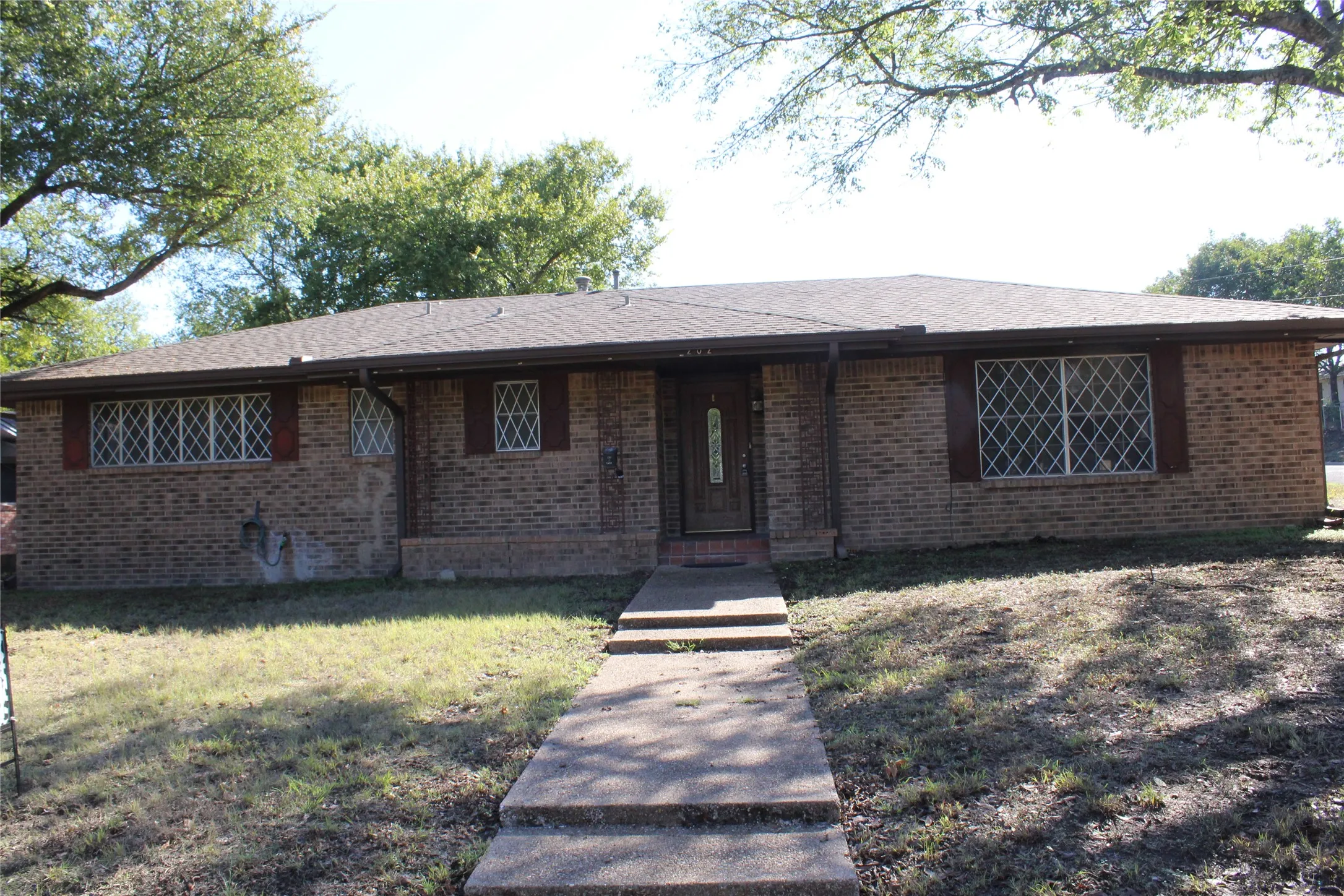 Brick exterior with decorative window grilles, a covered entry, and an asphalt shingle roof