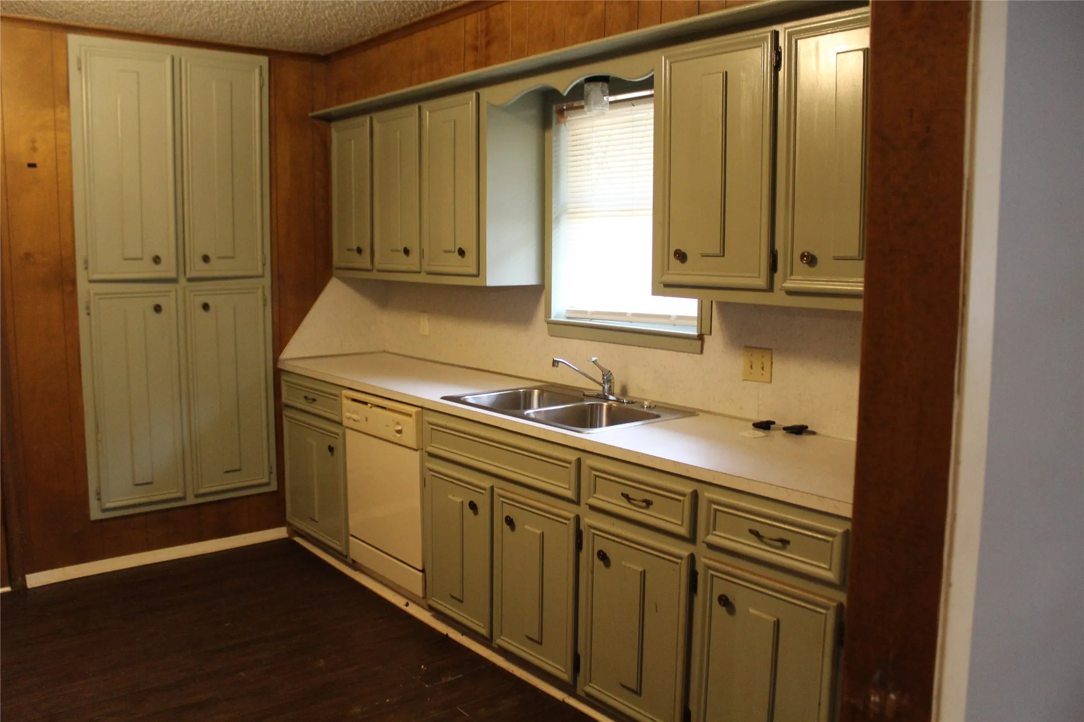 Kitchen featuring extensive cabinetry, laminate countertops, a double basin stainless steel sink, and wood-finish flooring