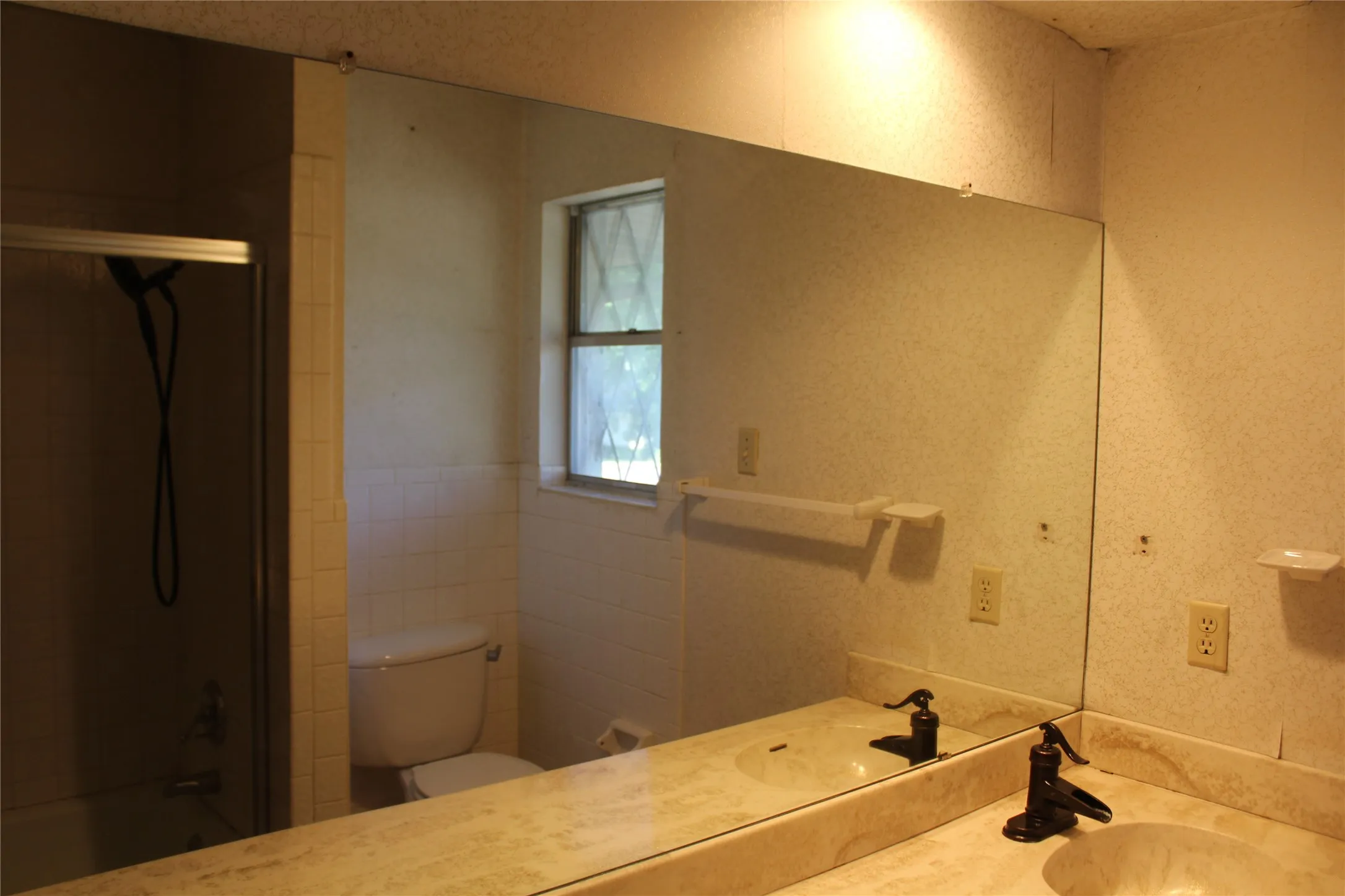 Full-width vanity mirror reflecting a window and shower enclosure
