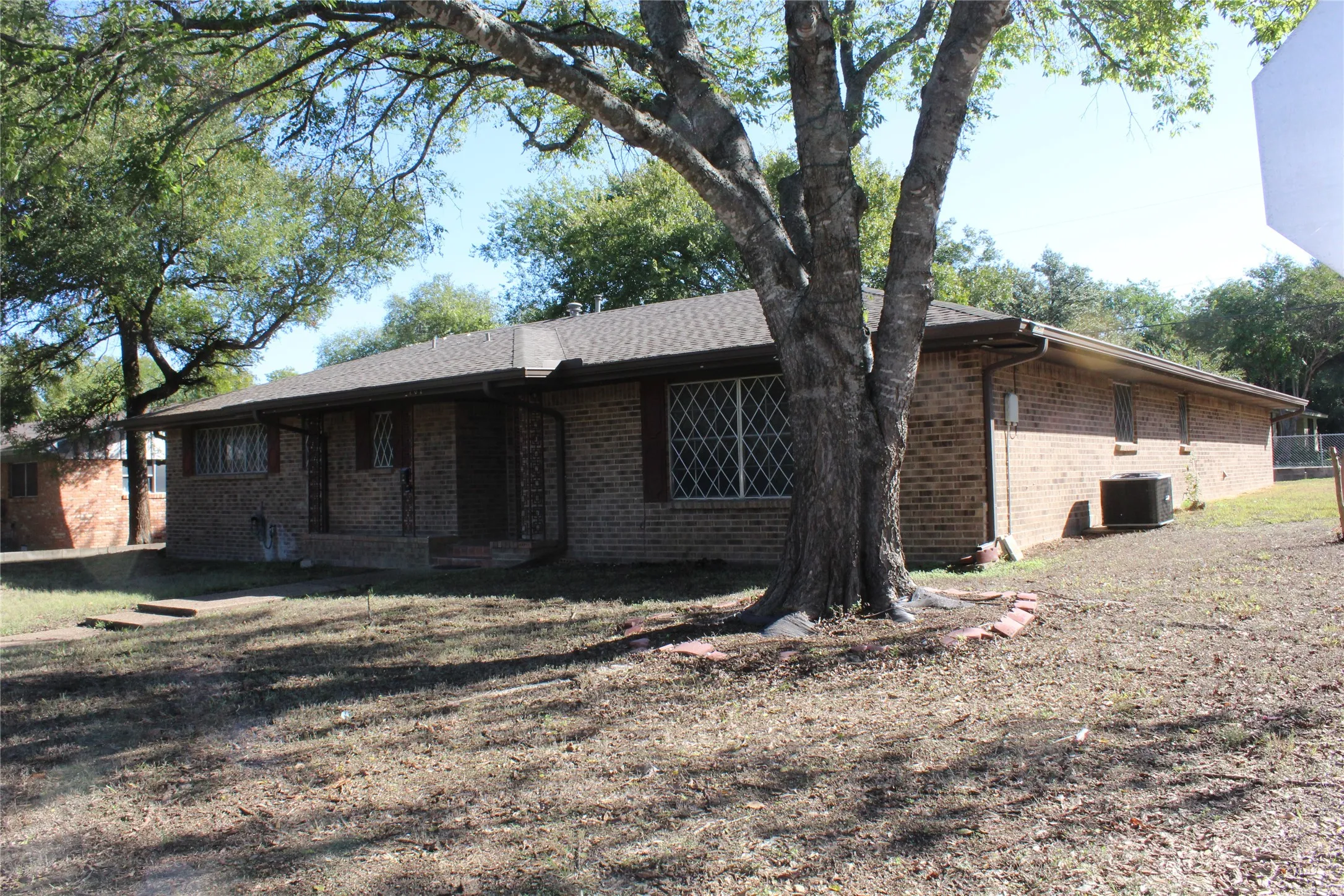 Brick exterior ranch home with a covered front porch and a mature tree