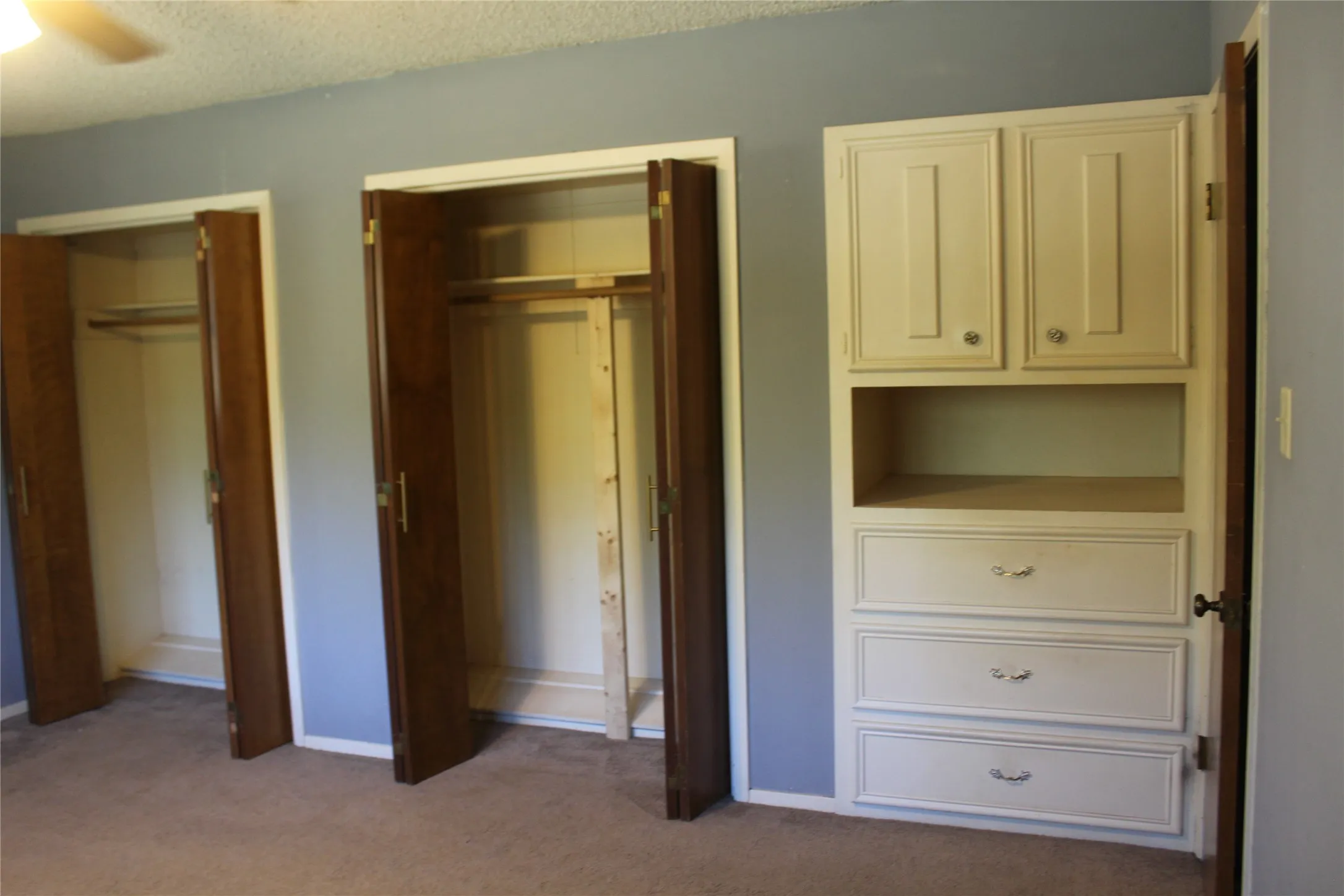 Two closets with bi-fold wood doors and a built-in storage unit with drawers and upper cabinetry