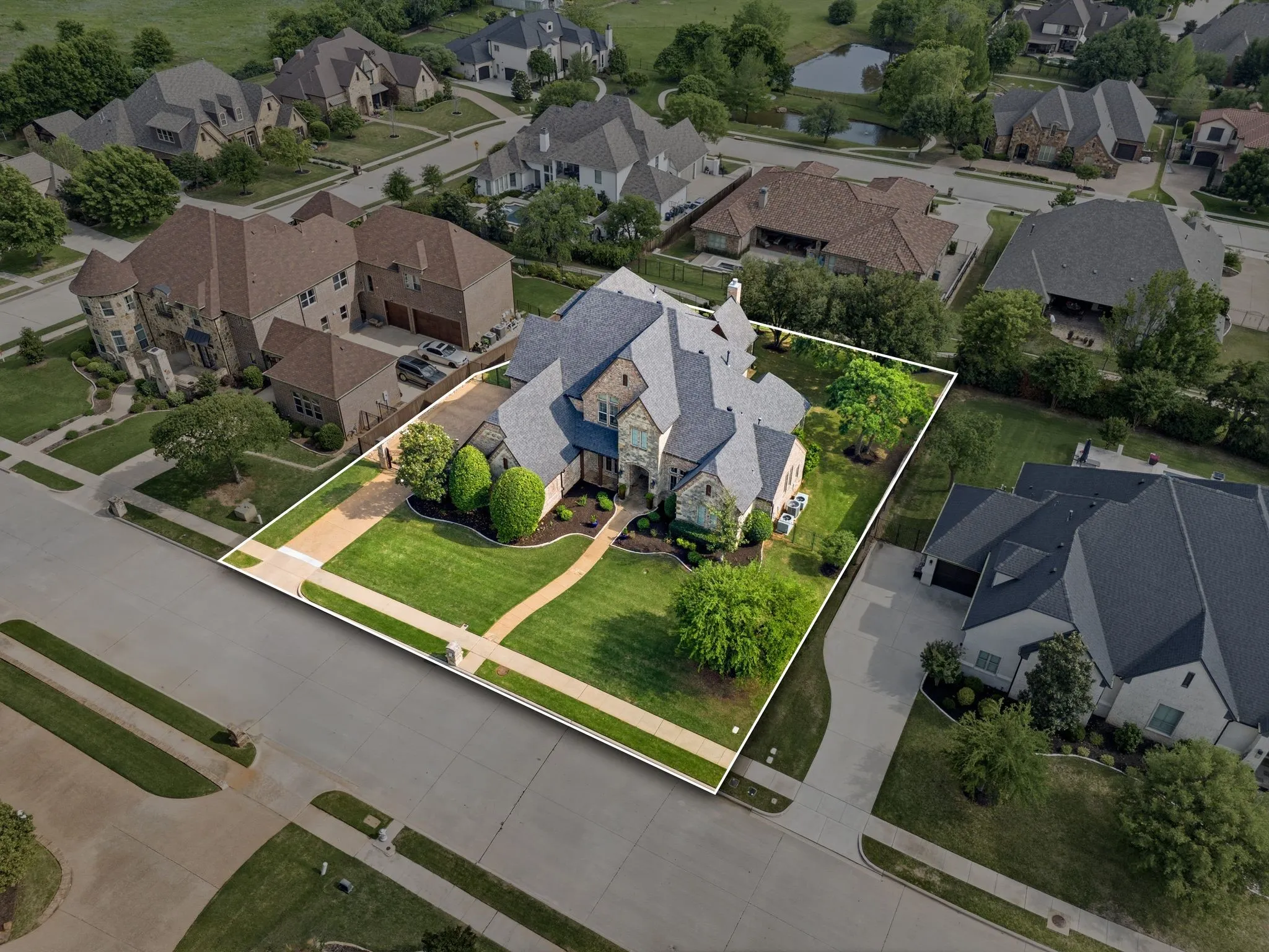 Stone and brick exterior with a multi-level roofline, extensive front lawn, mature trees, and a concrete pathway leading to the entrance