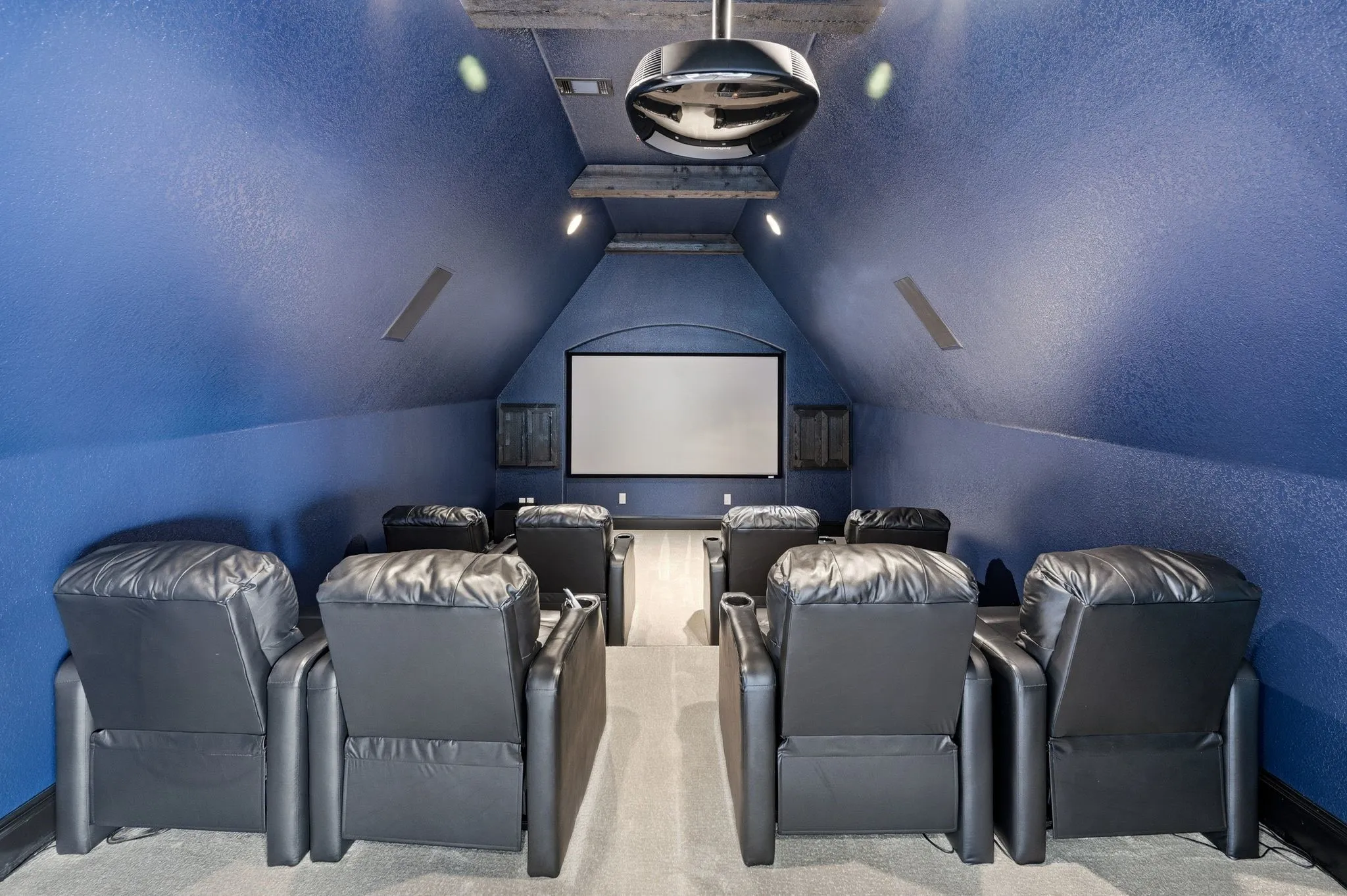 Dedicated media room featuring a projection screen, ceiling-mounted projector, and recessed lighting