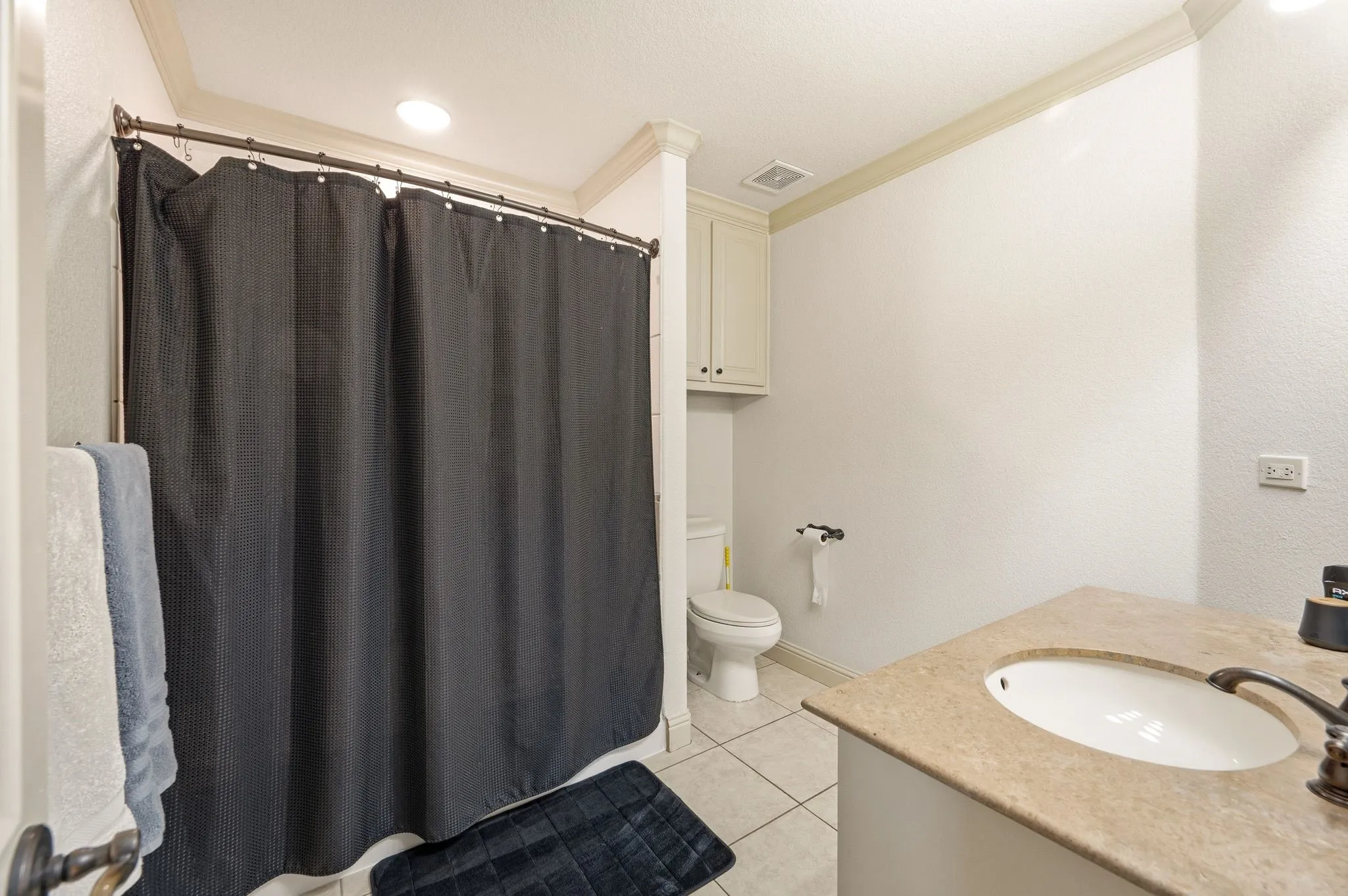 Vanity with oval basin sink, bronze-finish faucet, and light-tone countertop