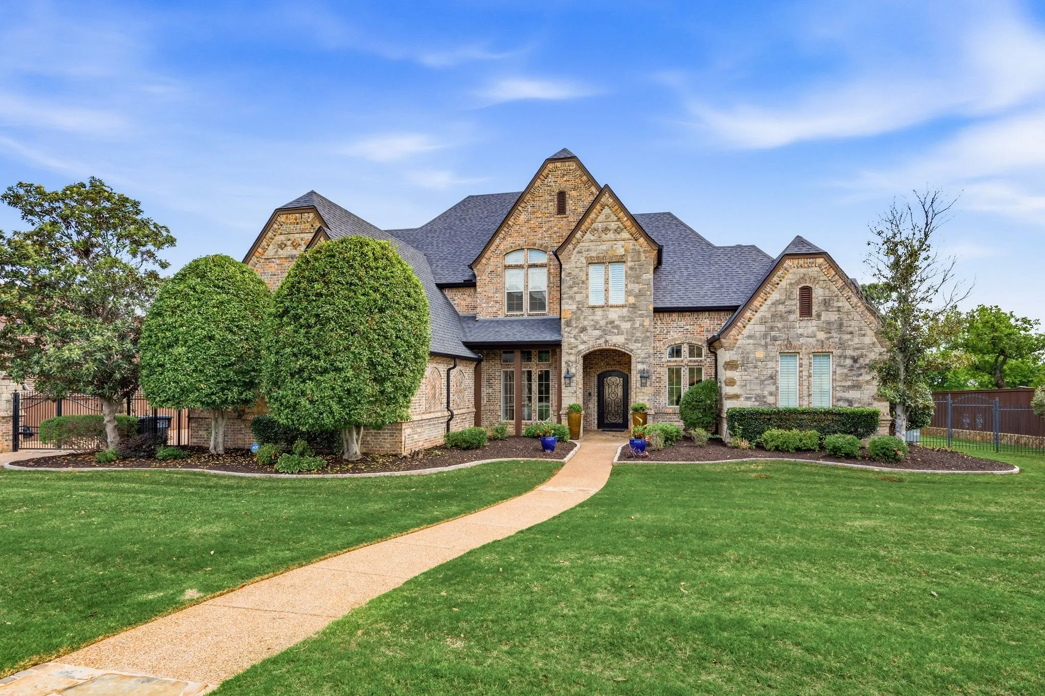 Stone facade residence featuring multiple gables and a dark shingle roof