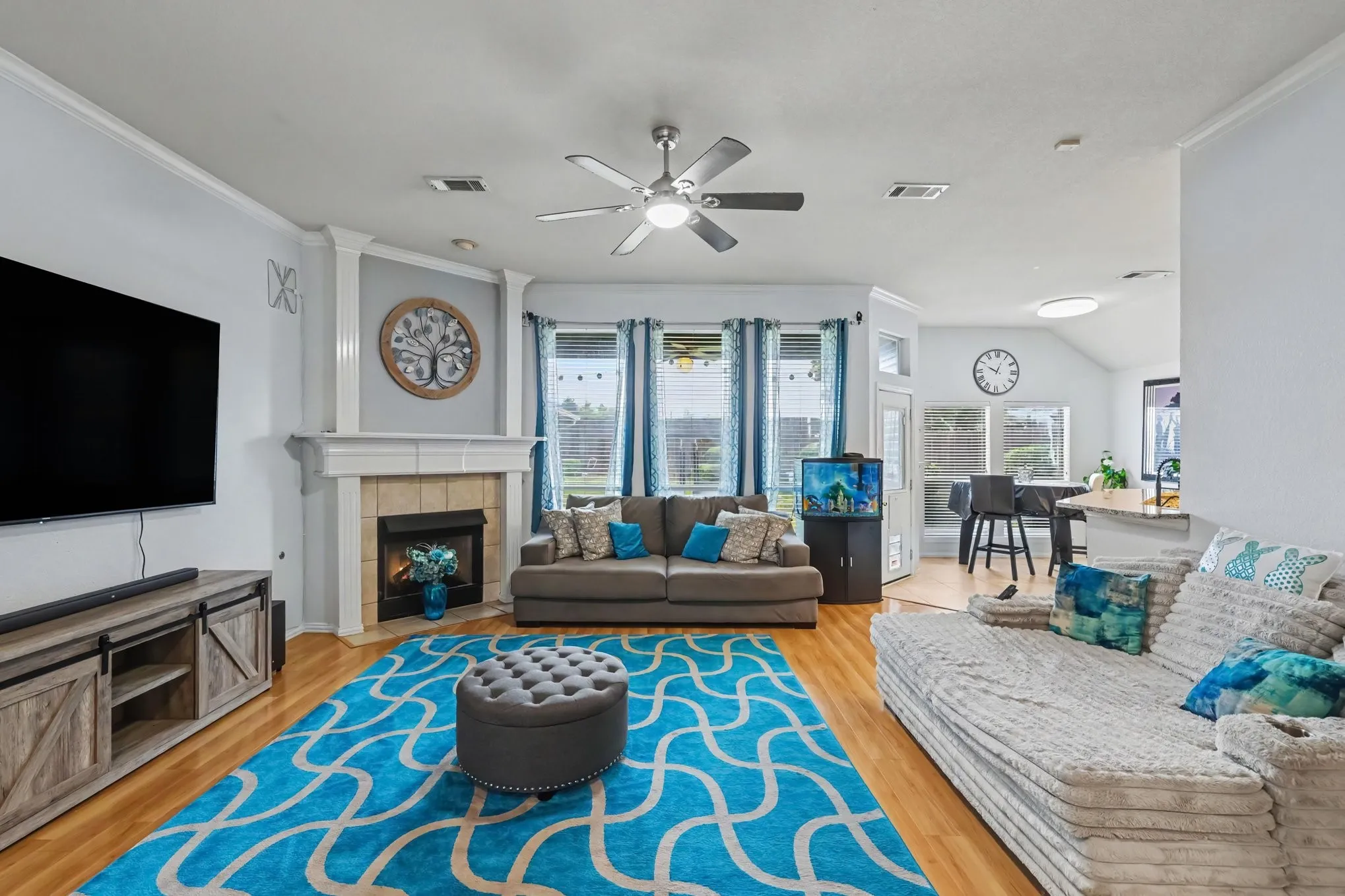 Open concept living space featuring wood-finish flooring, a corner fireplace with a tiled surround, and multiple windows