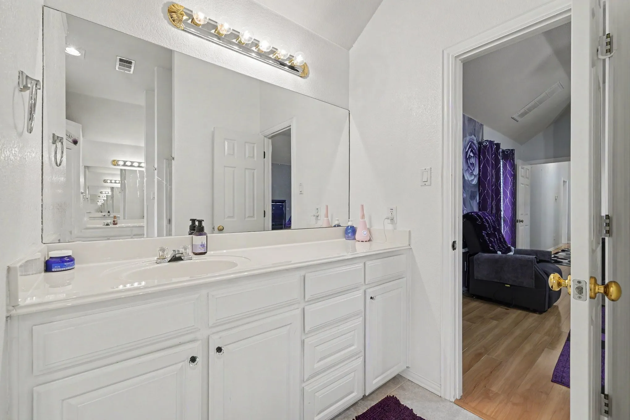 Extended vanity with integrated sink, white cabinetry, and wall-mounted light fixture