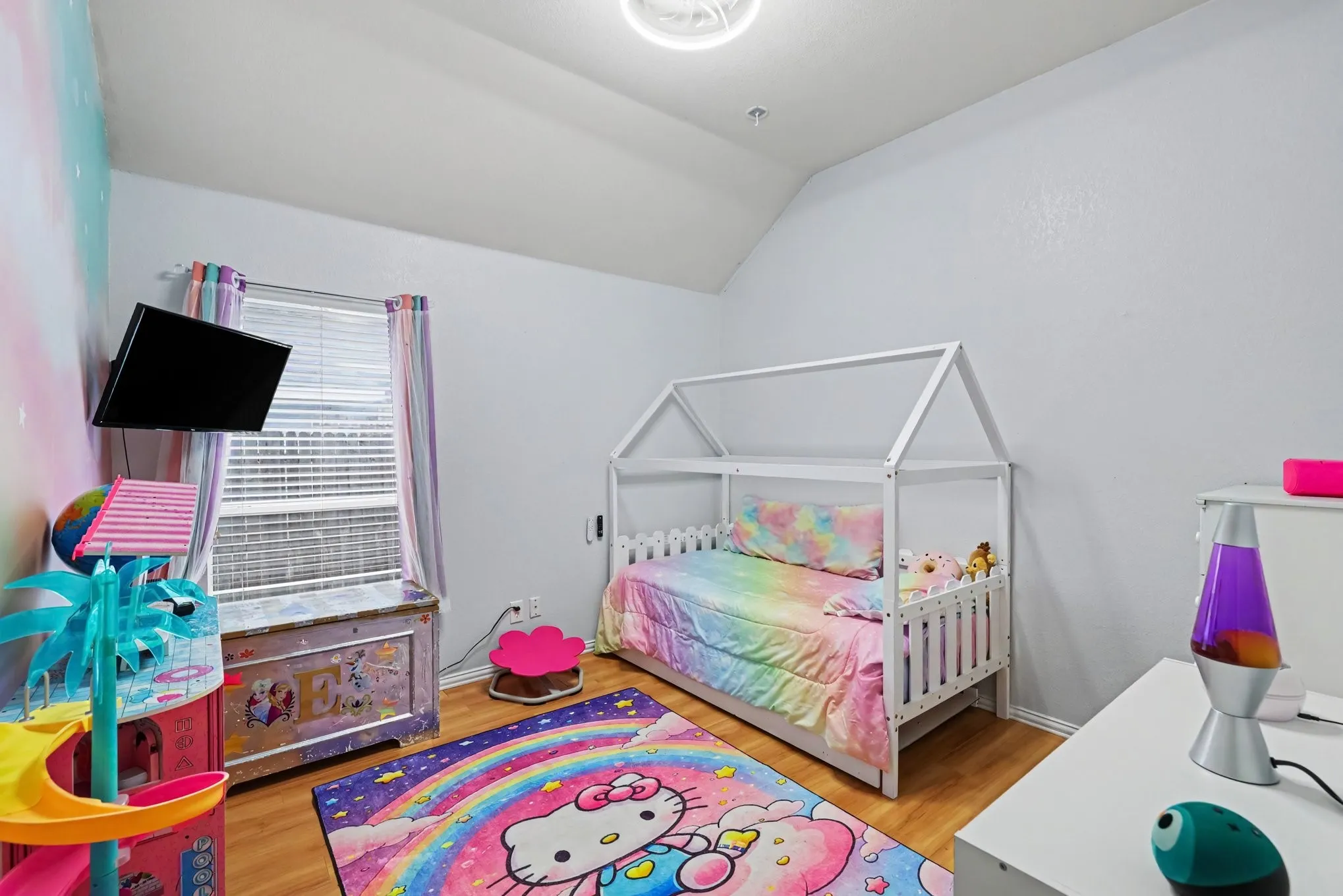 Wood-finish flooring with a window featuring blinds and light-colored walls