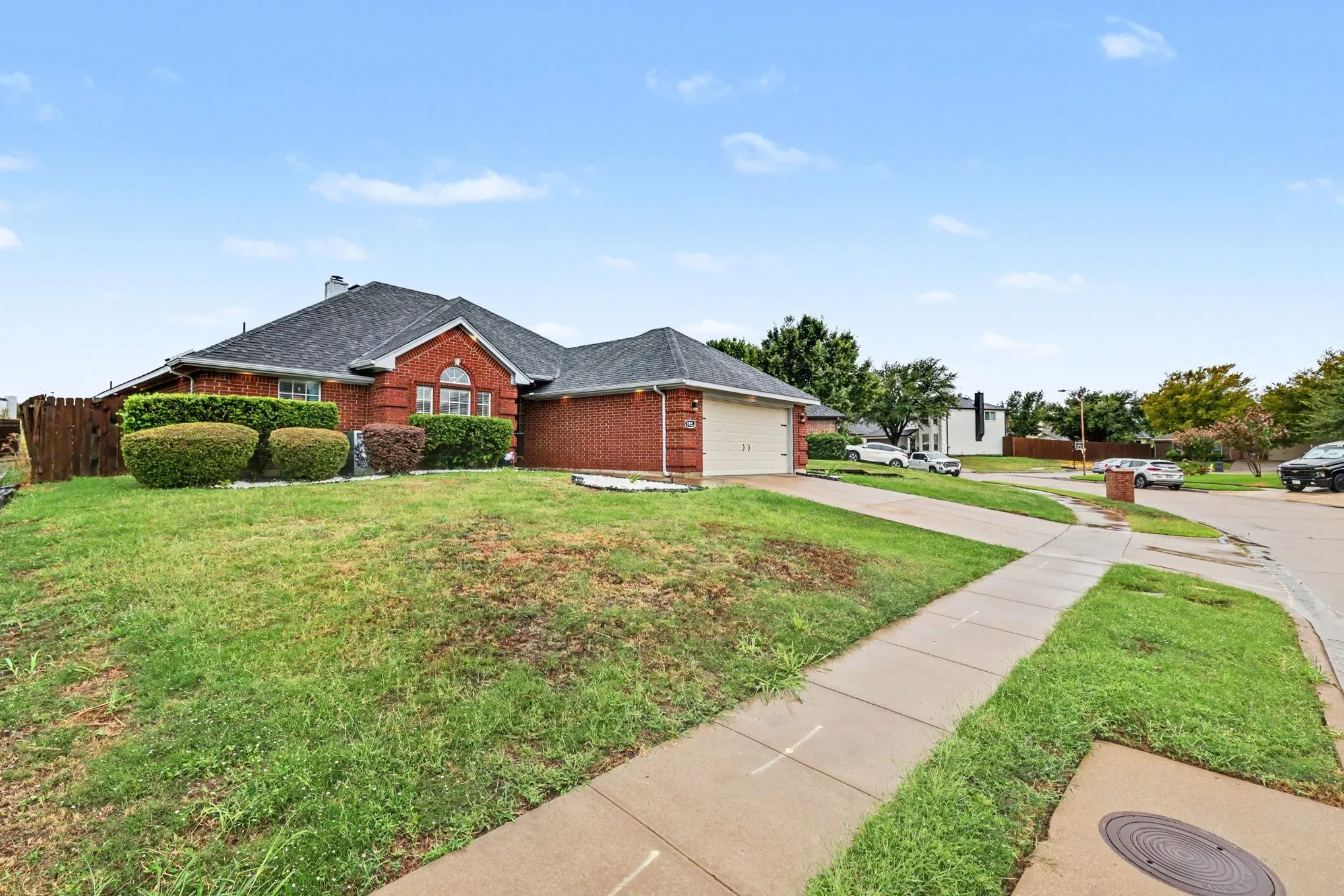 Red brick exterior with an arched window, a gabled roofline, and an attached two-car garage
