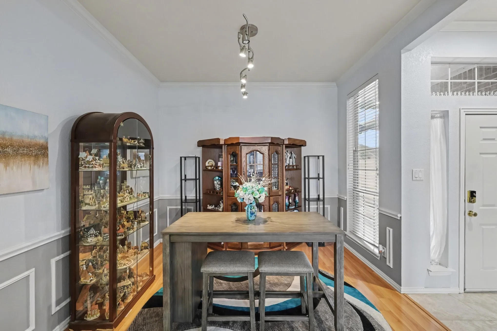 Hardwood-style flooring, white walls with wainscoting, and a white paneled door with transom windows