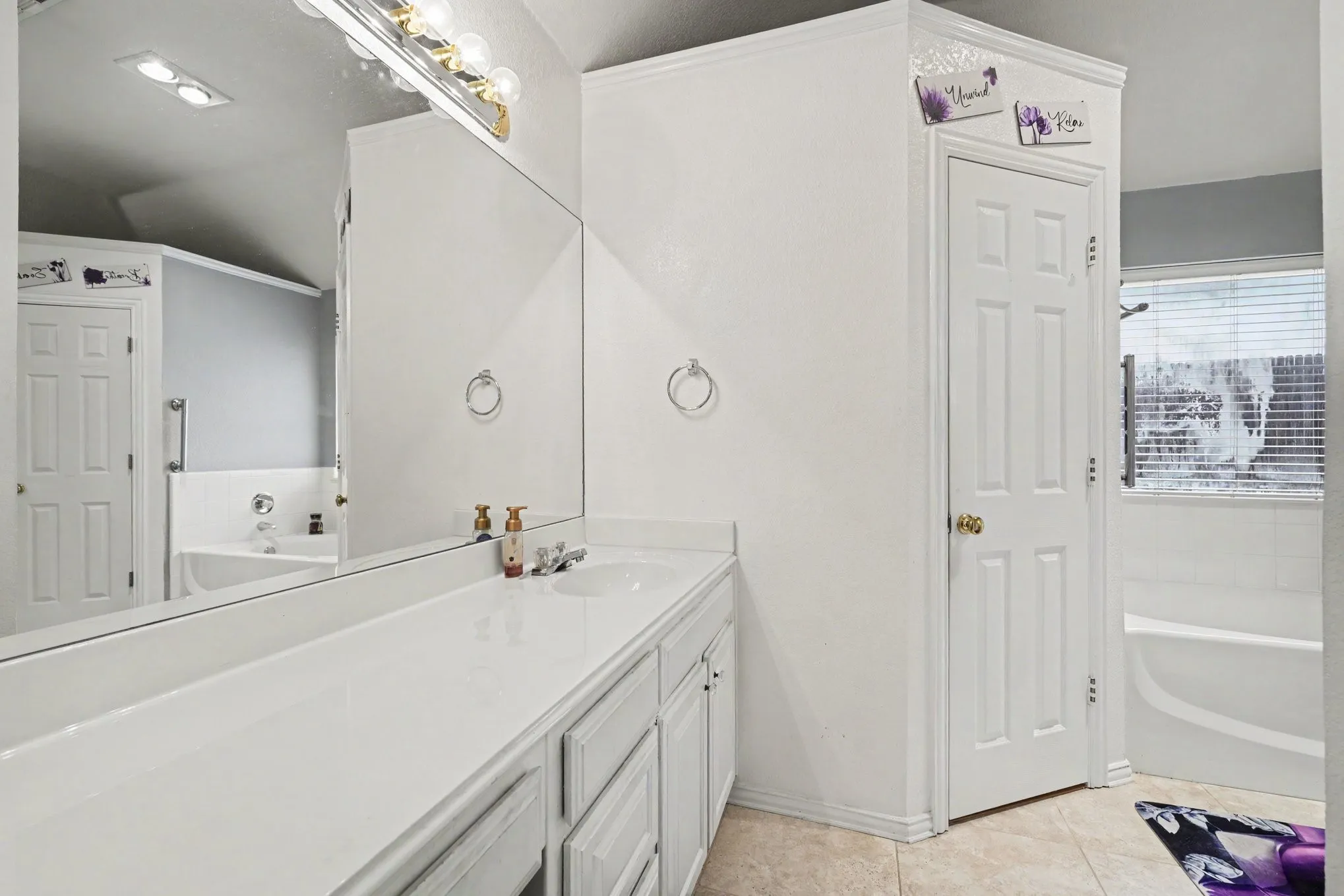 Double vanity with integrated sinks, large wall-mounted mirror, and overhead vanity lighting