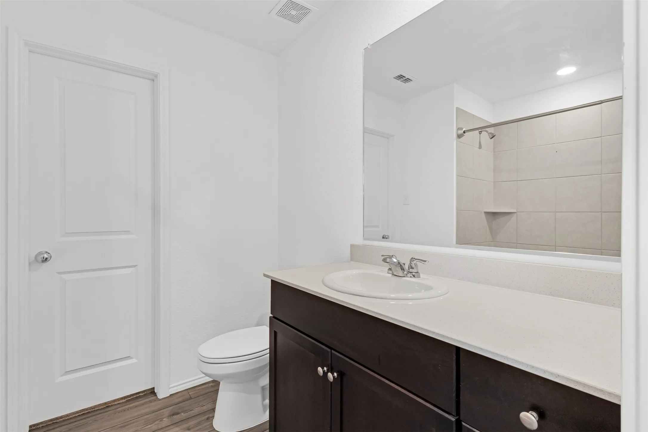 Bathroom featuring a dark wood-finish vanity with an undermount sink, light-toned countertop, and wood-finish flooring