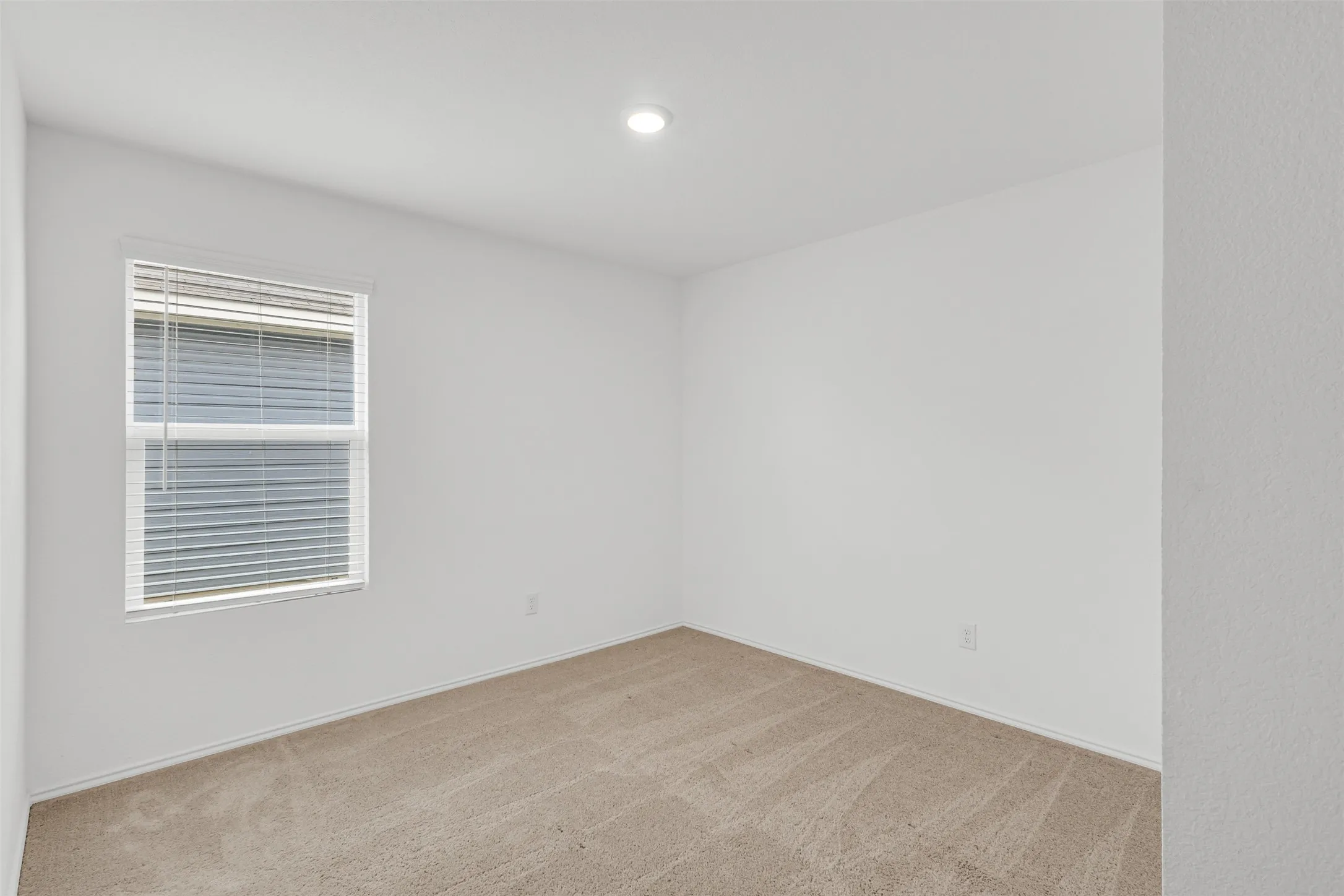 Recessed lighting, neutral tone carpeting, and a window with blinds