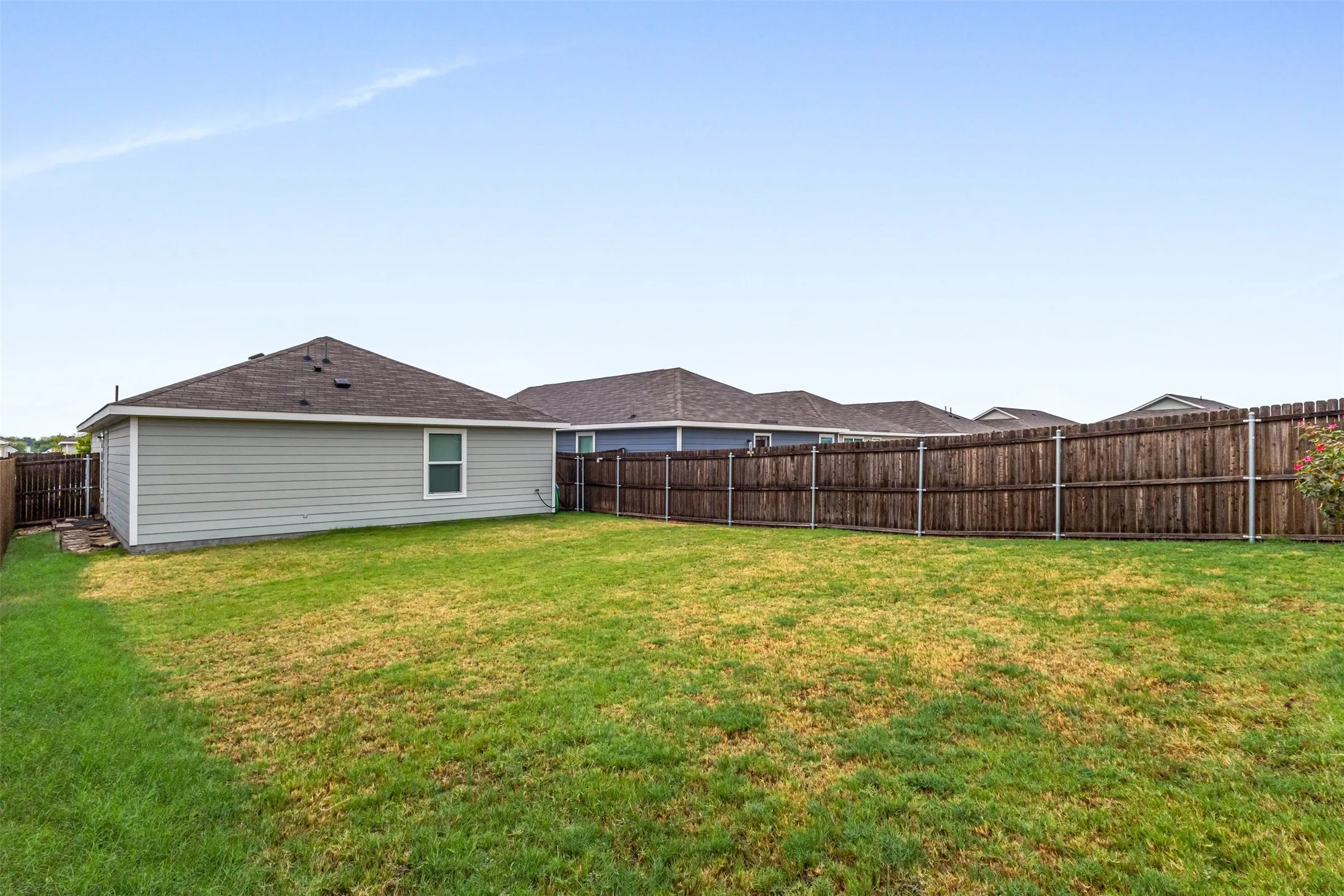 Expansive grassy lawn with a wood privacy fence