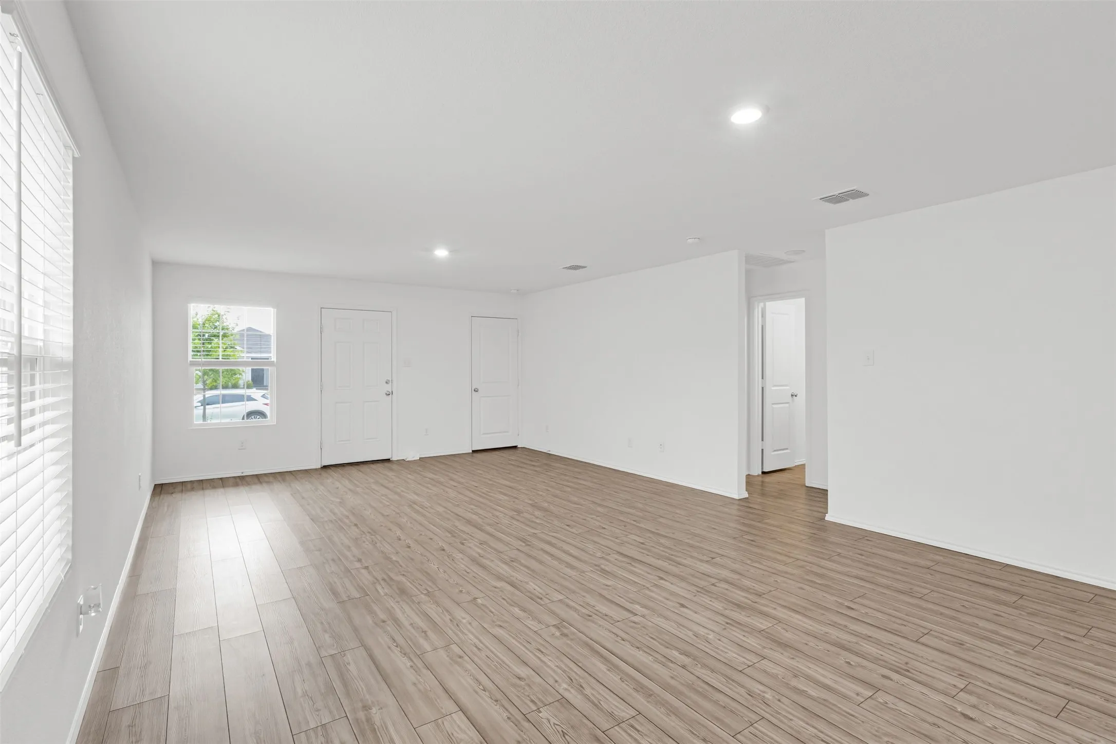 Spacious interior featuring wood-finish flooring, recessed lighting, and bright white walls