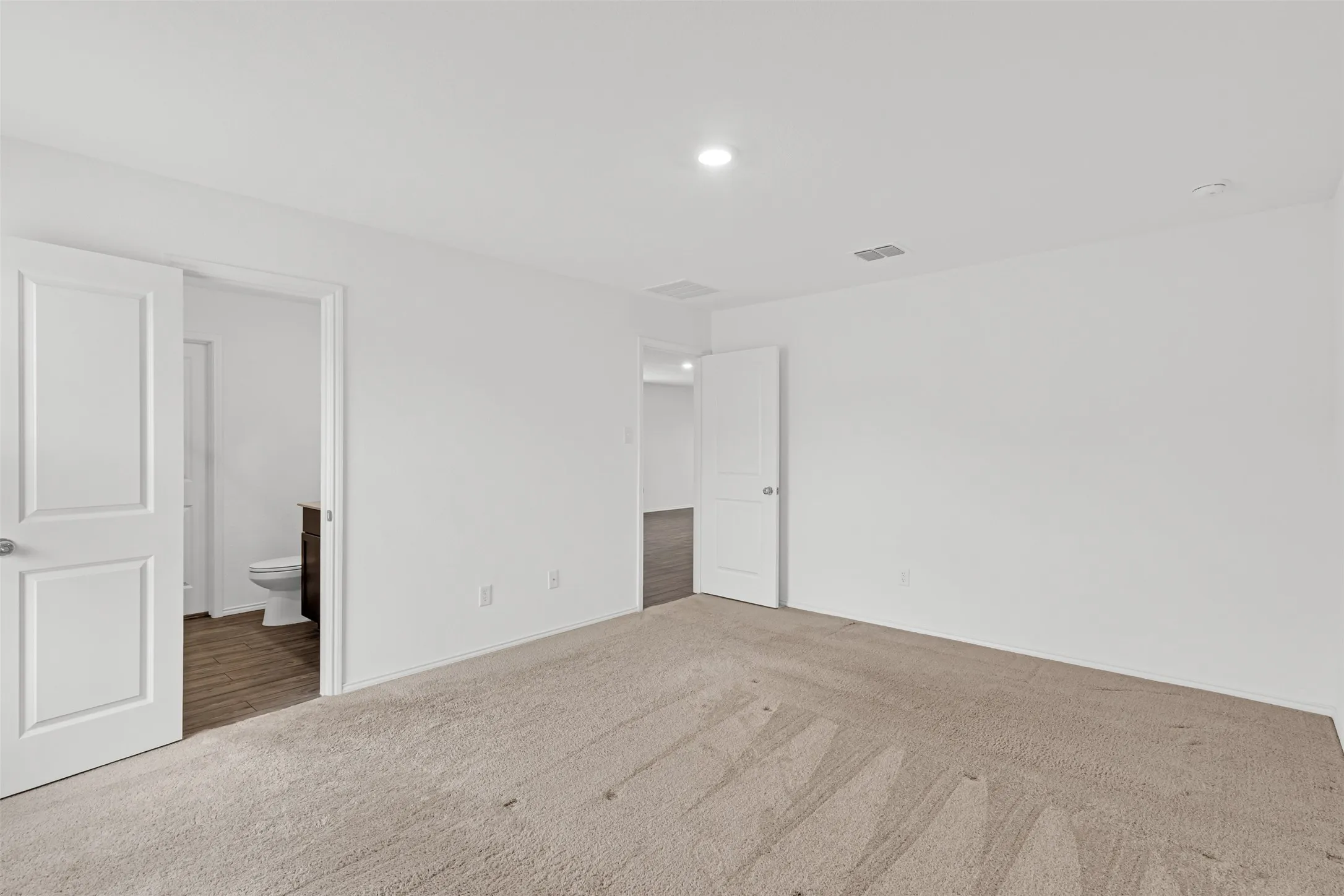 Neutral-toned wall-to-wall carpeting, white painted walls, recessed lighting, and white paneled doors