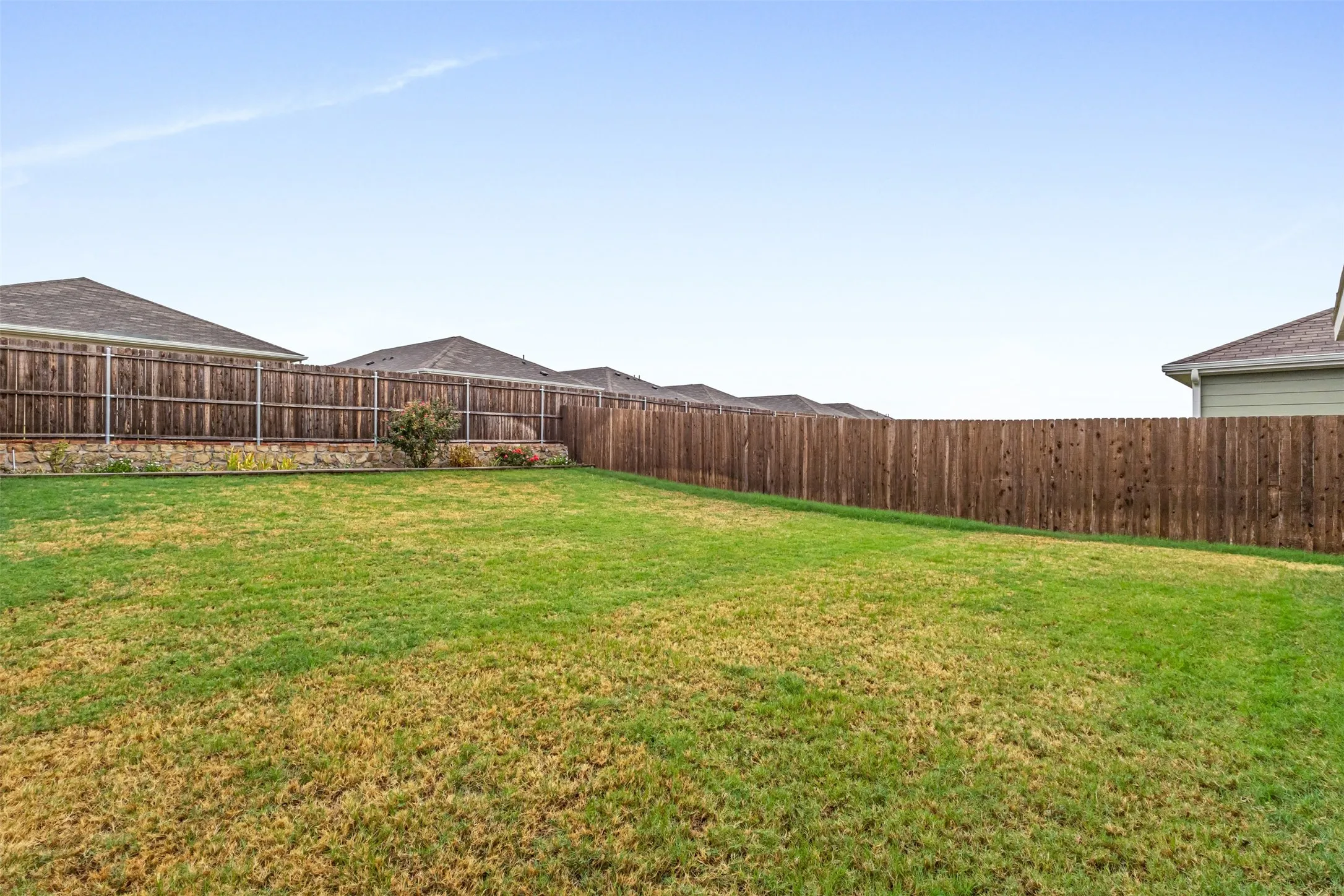 Expansive backyard featuring a large grass area and a wood privacy fence