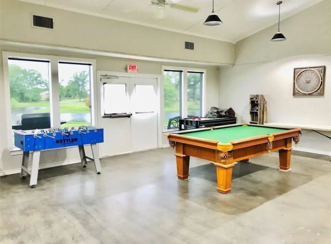 Concrete flooring, multiple windows, double doors, two pendant lights, ceiling fan
