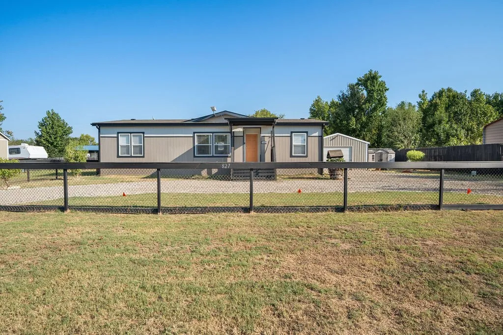 Chain-link fence with black top rail, gravel driveway, and a white and gray exterior with dark trim