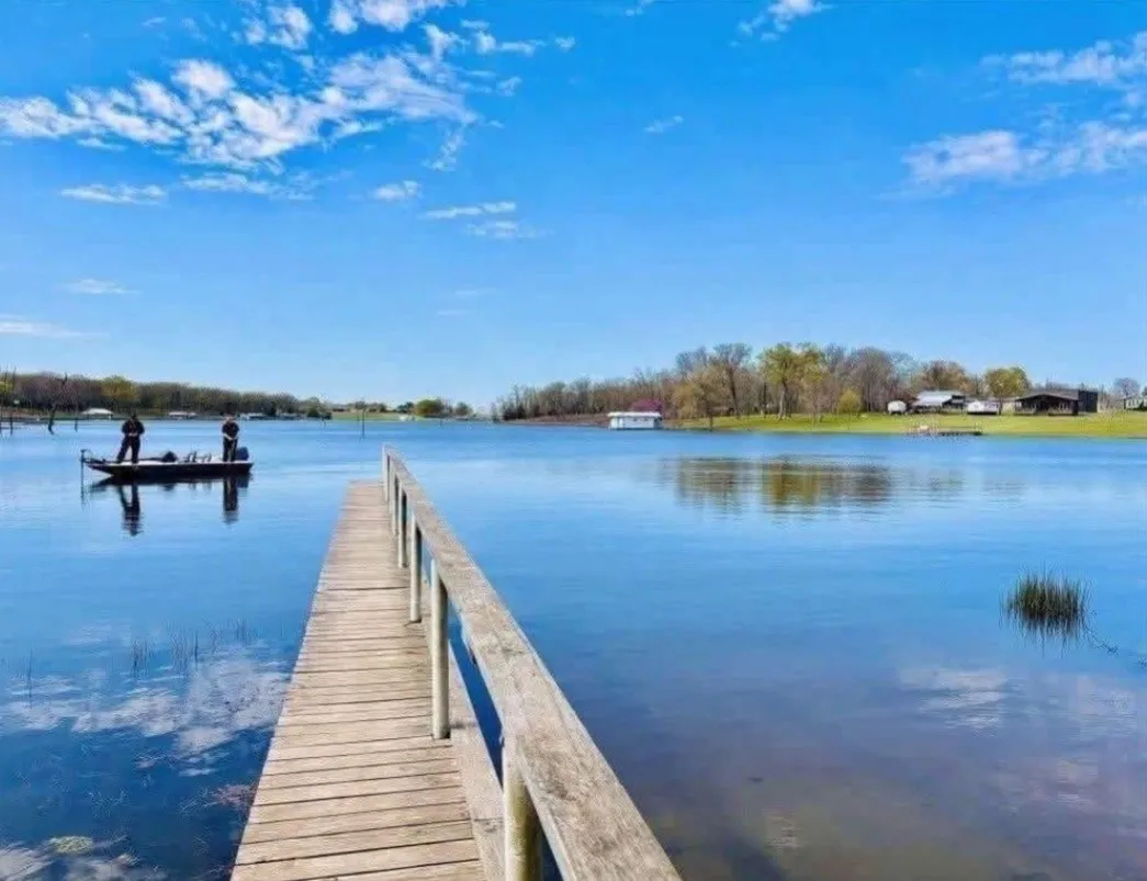 Wooden dock with handrail extending into a tranquil lake